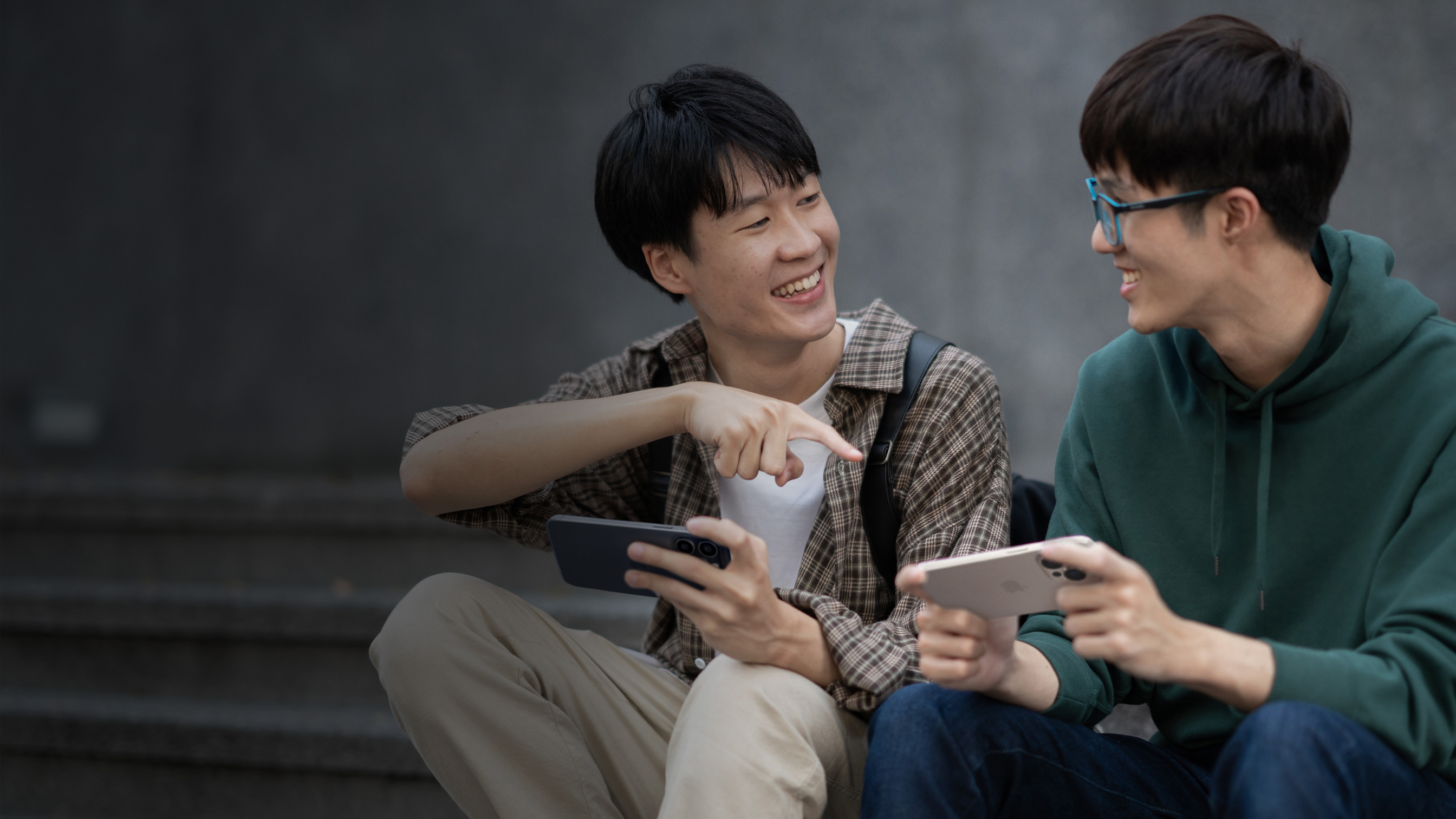 两个朋友微笑着在 iPhone 上玩游戏。	